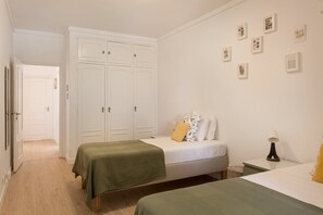 A bedroom with two beds, a wardrobe, and a wall with framed pictures. - The Cascais Hideaway (Cascais)