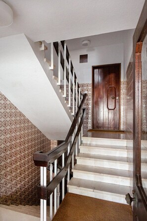 Un escalier avec une rampe en bois, un mur orné de motifs et une porte en haut.