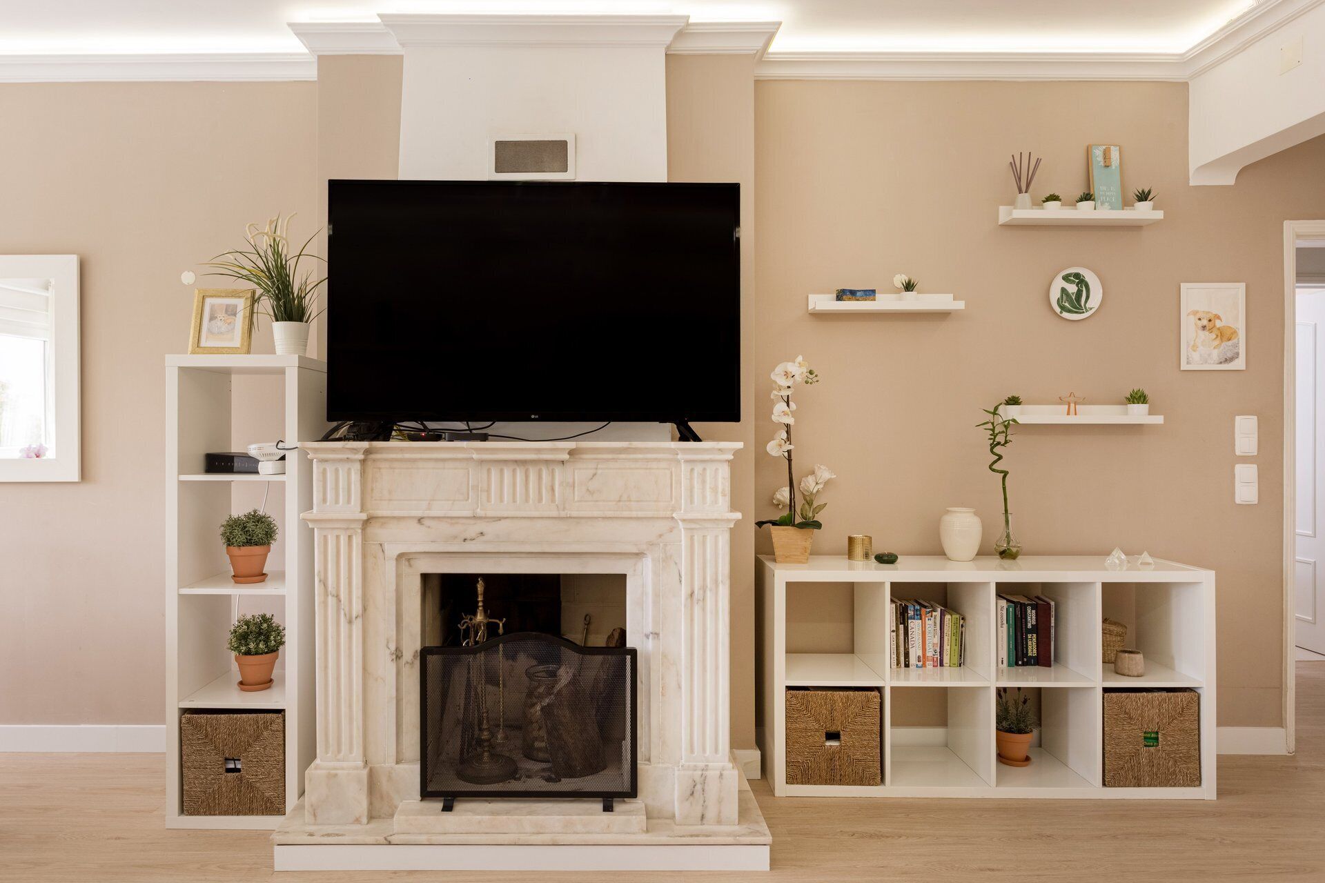 A living room with a fireplace, television, bookshelves, and decorative items.
