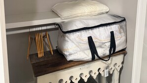 A closet with a bed, a hanging rack, and a storage unit with a bag. - Serene 1-bedroom condo with full kitchen, bathroom and AC close to Vanderbilt. (Nashville)