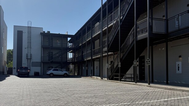 A multi-story building with a brick-paved courtyard, metal railings, and a car parked in the background. - Serene 1-bedroom condo with full kitchen, bathroom and AC close to Vanderbilt. (Nashville)