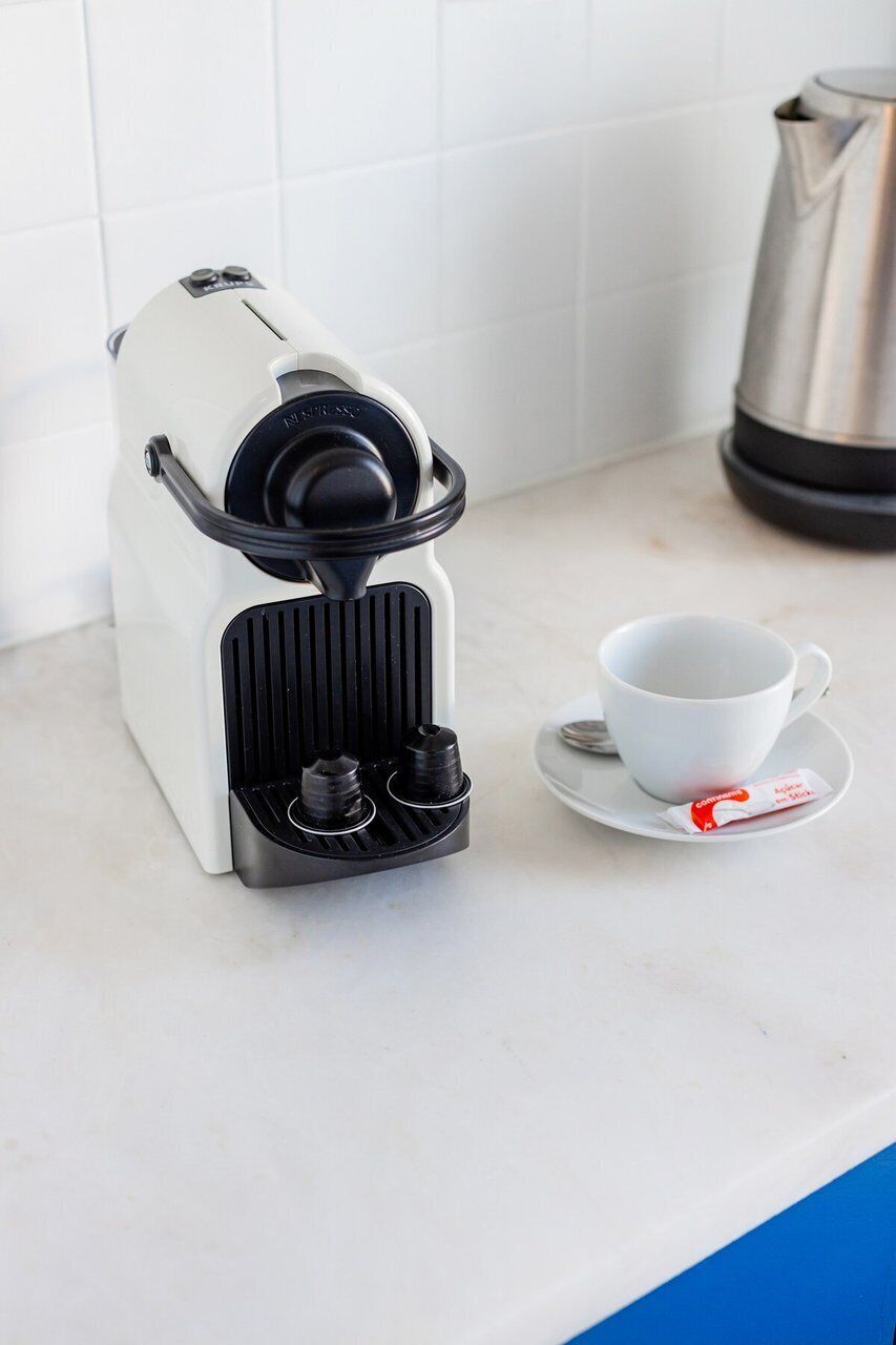Una cafetera con una taza y un plato sobre una encimera.