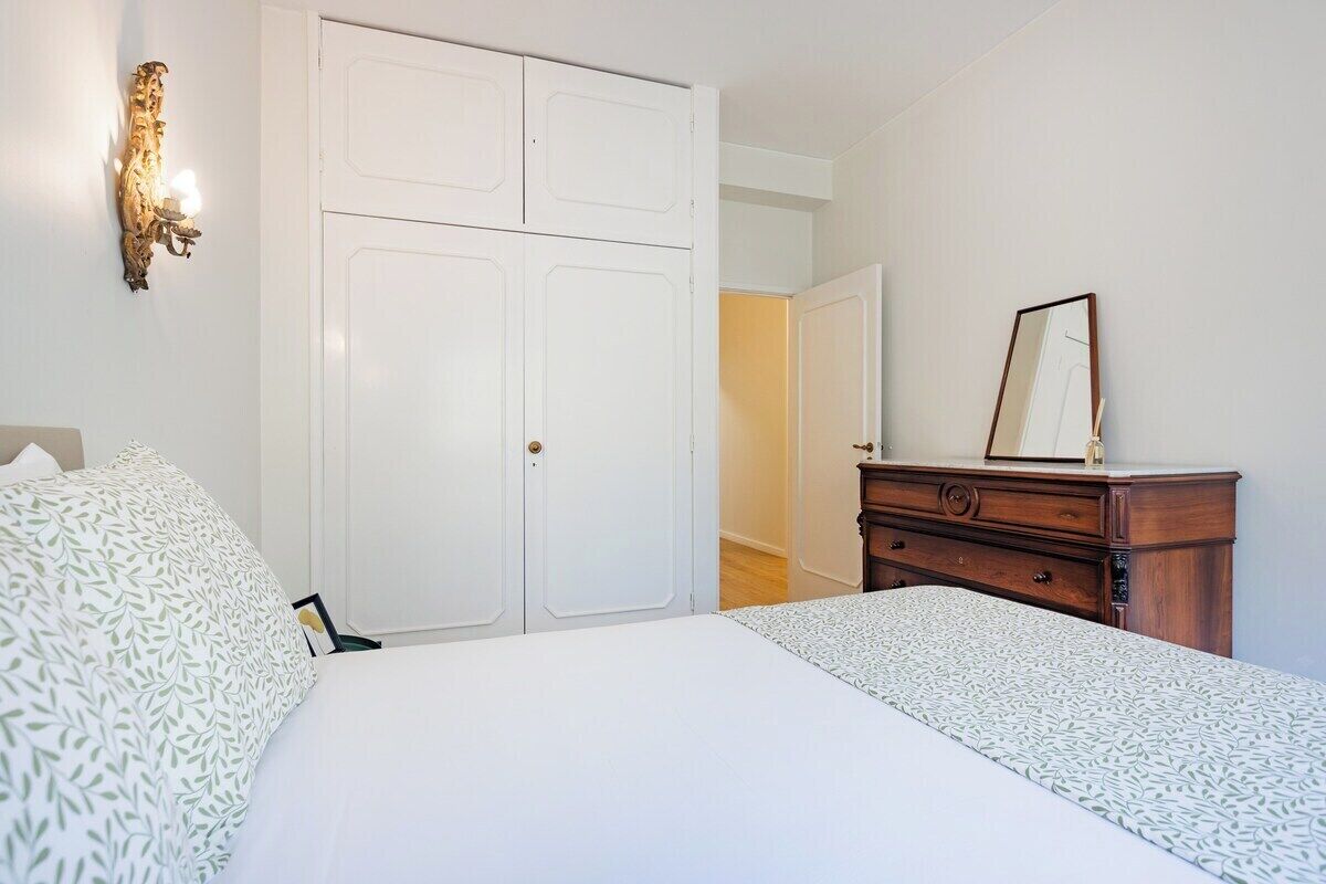 A bedroom with a bed, a dresser, a mirror, and a wardrobe.