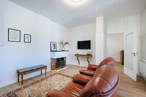 Ein Wohnzimmer mit Ledersofa, Kamin, Fernseher und einem gemusterten Teppich.