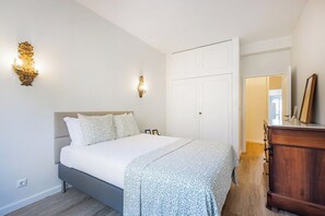 Ein Schlafzimmer mit einem Bett, Nachttischlampen, einem Kleiderschrank und einer Tür.