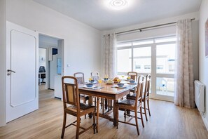 Ein Essbereich mit einem Holztisch, sechs Stühlen und Blick durch ein großes Fenster.
