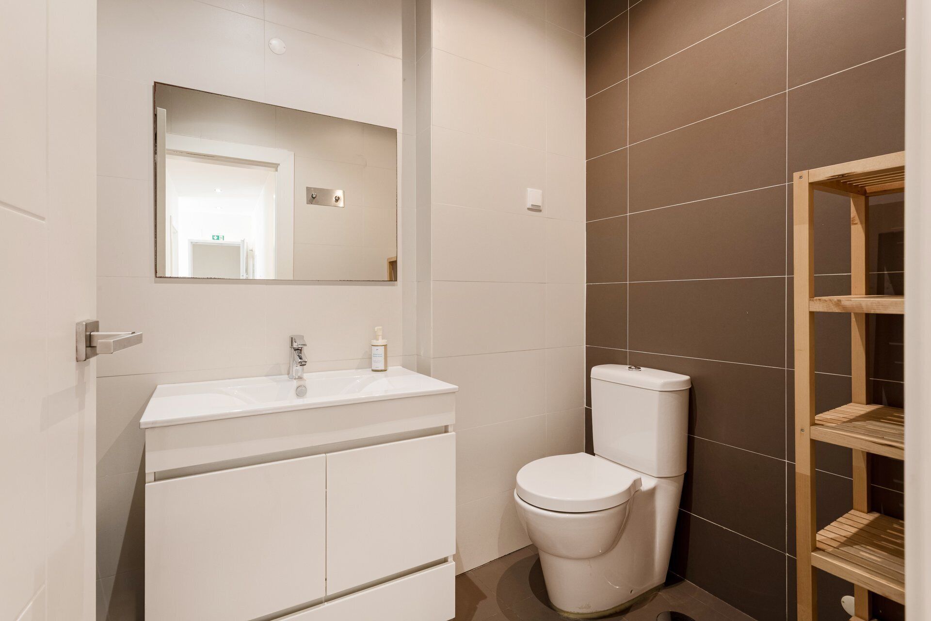 A modern bathroom with a white sink, a toilet, and a mirror above the sink.