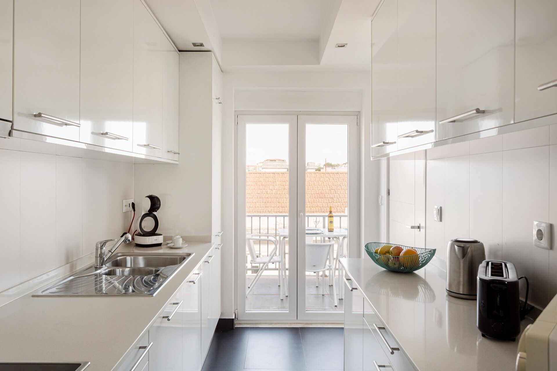 Een moderne keuken met witte kasten, een roestvrijstalen spoelbak, een koffieapparaat en een broodrooster.