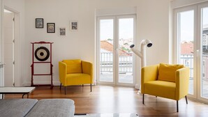 Ein modernes Wohnzimmer mit zwei gelben Sesseln, einem roten und schwarzen Dekorationsobjekt und einer weißen Heizung.
