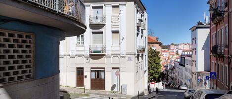 Una calle estrecha con edificios, un paso de peatones y coches aparcados.