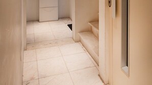 Ein schmaler Gang mit einer weißen Tür rechts, einer eingelassenen Deckenleuchte und einem weißen Schrank im Hintergrund.