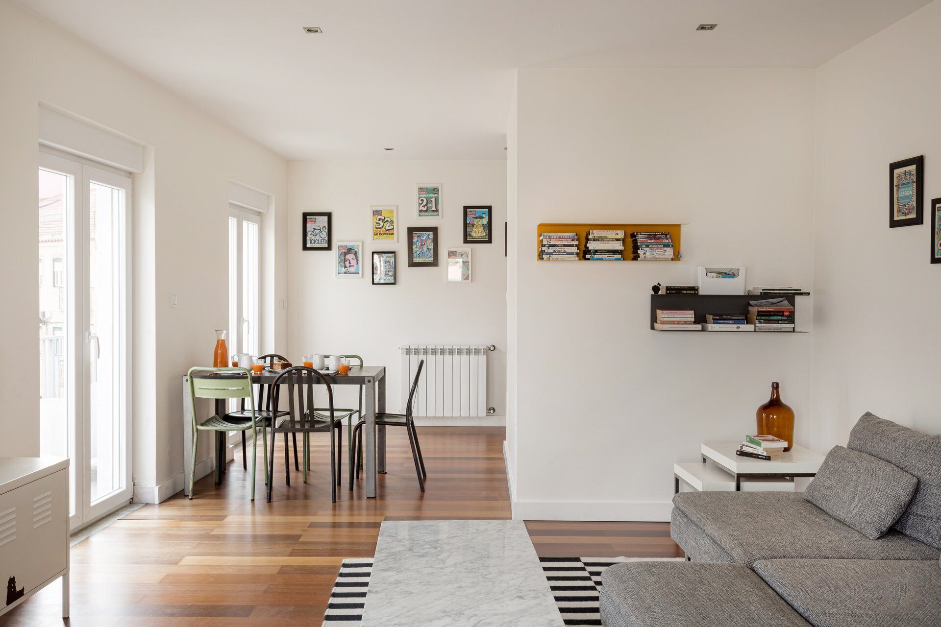 En moderne stue med spiseplads, sofa, bogreoler og en radiator.