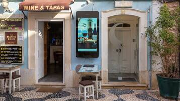 A restaurant named 'Wine & Tapas' with a menu board, outdoor seating, and a guest house entrance.