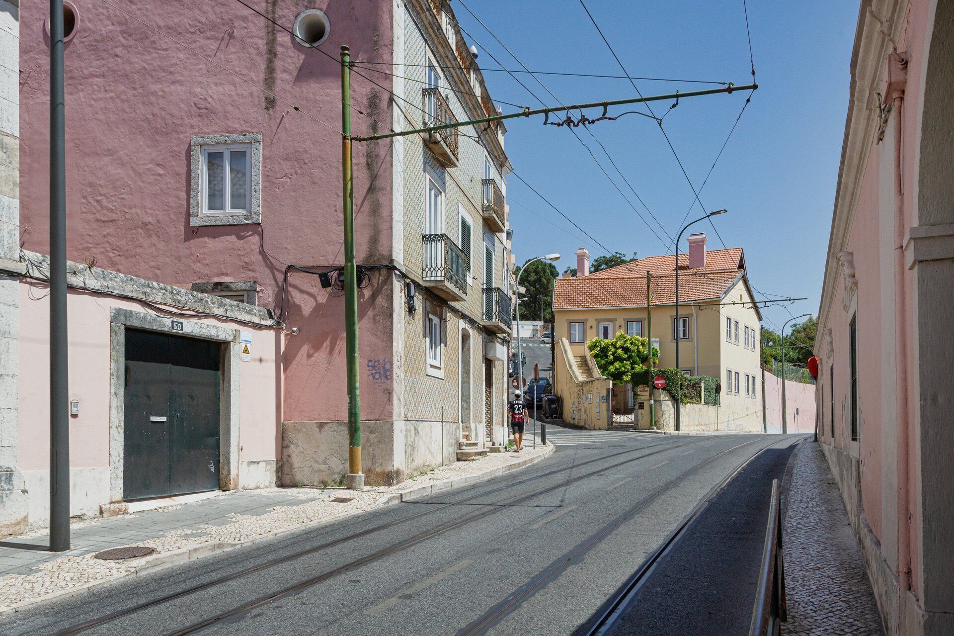 A narrow street with buildings on both sides, a tram track, and a pedestrian crossing.