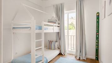 A bunk bed room with a window, curtains, and a green wall decoration.