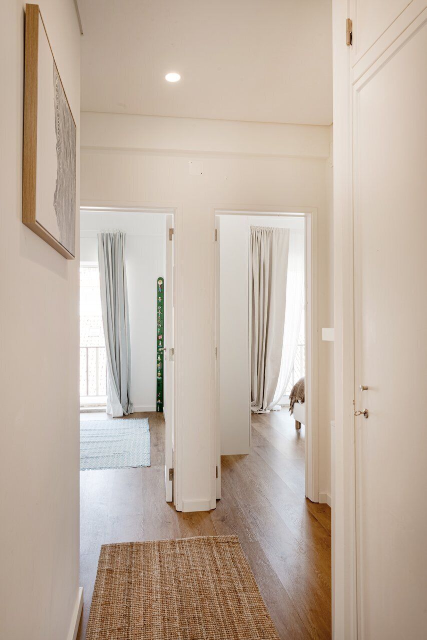 A hallway with white walls, wooden flooring, and a framed picture on the left.