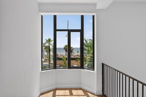 A corner room with a large window overlooking a beach with palm trees and a clear sky. - Casa Del Sol SeaSide (Durrës)