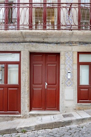 Ein Gebäude mit zwei roten Türen, einer Steinaußenwand und einem Metallbalkon.