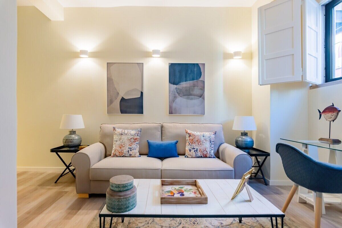 A living room with a sofa, two side tables, a coffee table, and wall-mounted lighting.