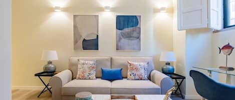 A living room with a sofa, two side tables, a coffee table, and wall-mounted lighting.