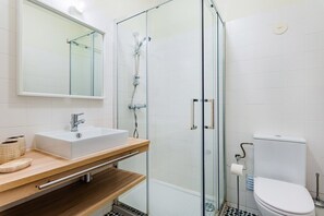 Ein modernes Badezimmer mit Duschkabine aus Glas, einem weißen Waschbecken und einer Toilette.