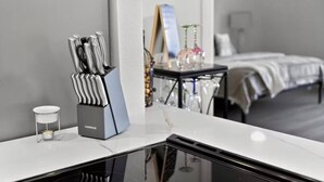 Ett hotellrum med en modern köksbänk, en uppsättning knivar, ett litet ljus och en säng med ett vitt överkast.