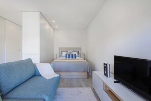 Ein Schlafzimmer mit einem Bett, einem Fernseher, einem Sofa und einem Kleiderschrank.