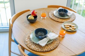 A wooden dining table with two bowls, a plate of cookies, and a glass of orange juice. - Executive Studio AC & Parking, Palácio de Cristal (Porto)