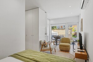 A modern bedroom with a bed, a desk, a chair, and a balcony with outdoor furniture. - Porto Garden | Patio Retreat (Porto)