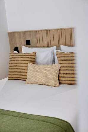 A bed with a wooden headboard, white bedding, and striped pillows. - Porto Garden | Patio Retreat (Porto)