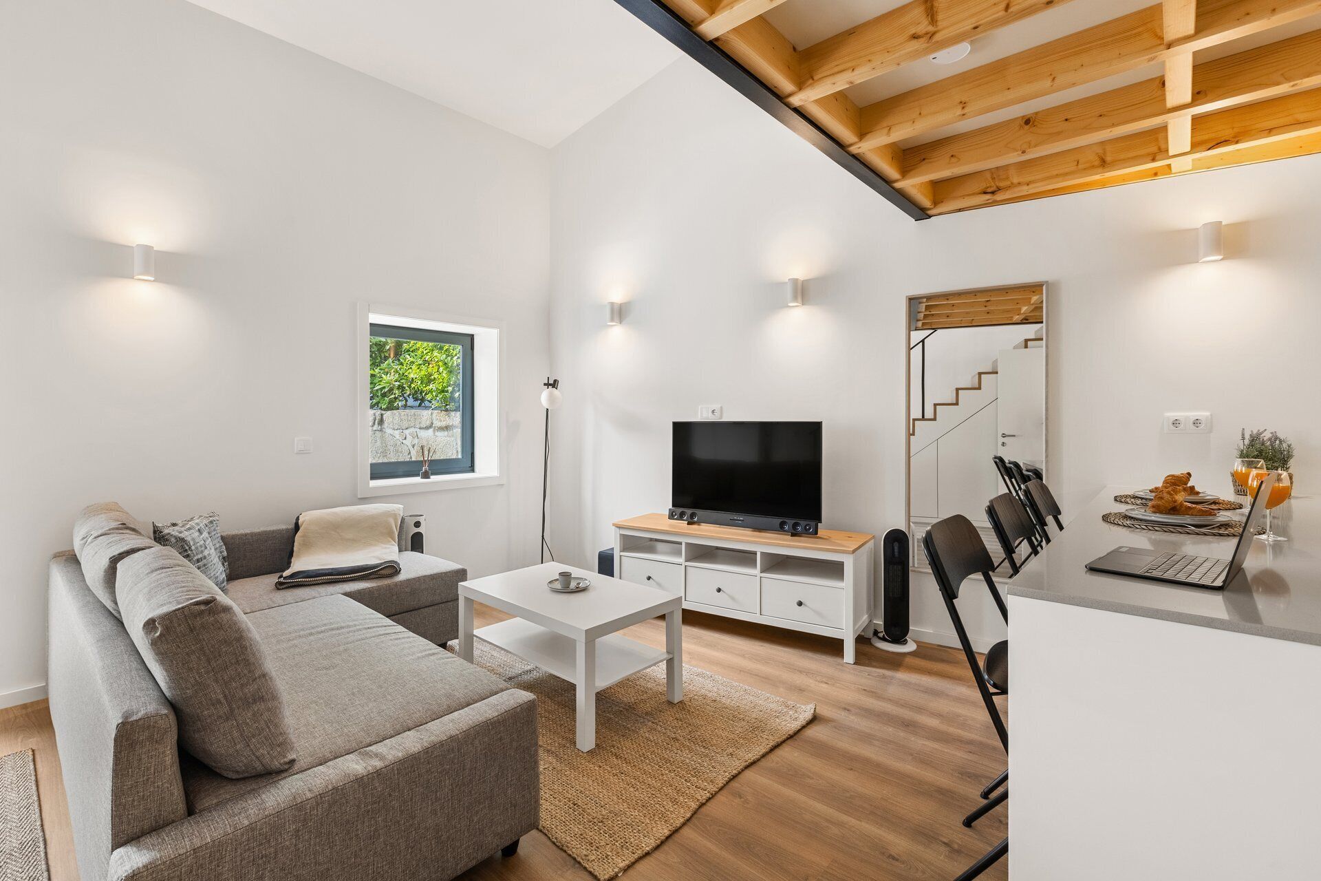 A modern living room with a sofa, TV, and dining area.