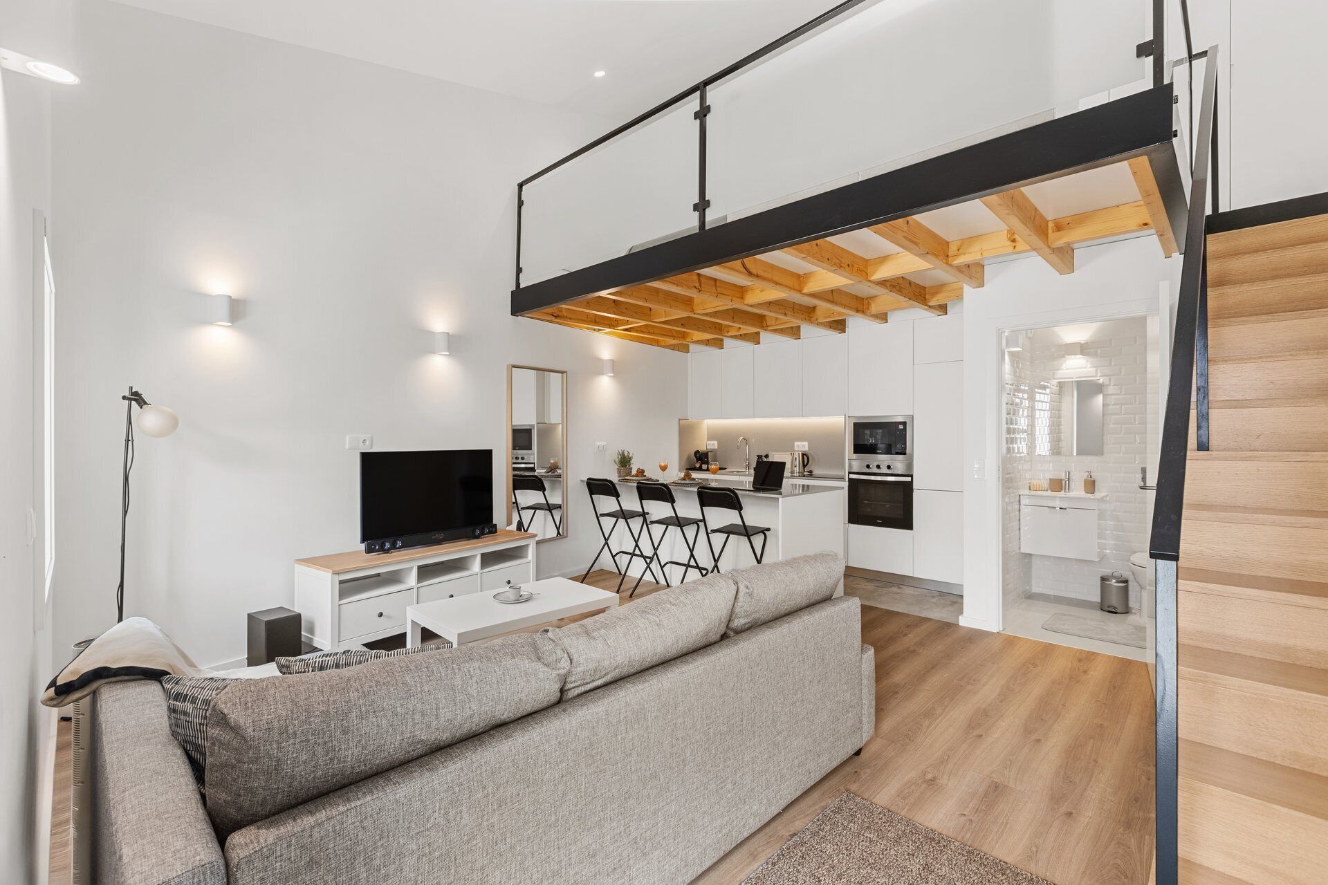A modern living room with a sofa, TV, and dining area.
