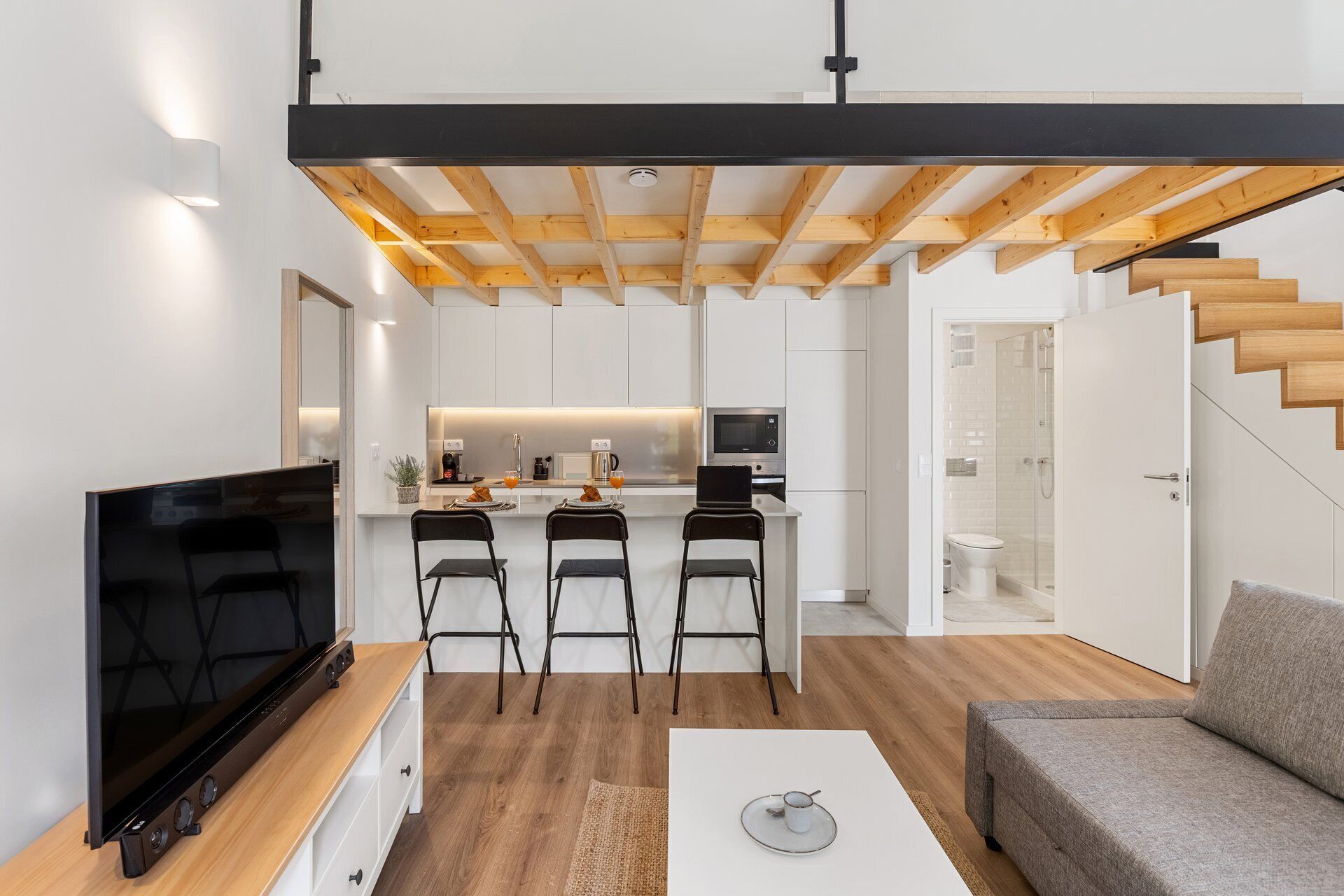 Une cuisine moderne avec des meubles blancs, un îlot central et un coin repas équipé de trois chaises.