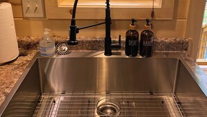 A kitchen with a stainless steel sink, wooden walls, a window with a view of trees, and a granite countertop. - NEW LISTING~Quiet~cozy~clean~fast WIFI, Dollywood, hotub/FP #9 (Sevierville)