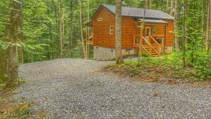 A wooden cabin with a gravel driveway, surrounded by a forest. - NEW LISTING~Quiet~cozy~clean~fast WIFI, Dollywood, hotub/FP #9 (Sevierville)