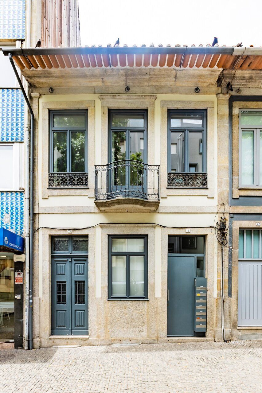 Un immeuble à plusieurs étages doté d’un balcon, d’une porte double et d’une petite fenêtre.