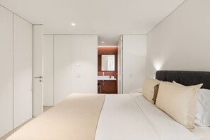 Una camera da letto con un letto, un armadio e un bagno visibile attraverso una porta aperta.