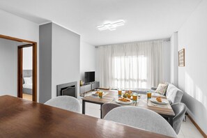Ein modernes Wohnzimmer mit Essbereich, Fernseher und einer Couch.