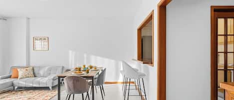 A modern living room with a dining table, sofa, and chairs.