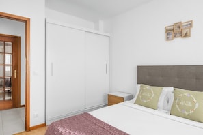 Ein Schlafzimmer mit Bett, Kleiderschrank, Nachttisch und einer Wand mit gerahmten Bildern.