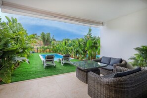 Eine Terrasse mit Pool, Korbmöbeln und üppiger Bepflanzung.
