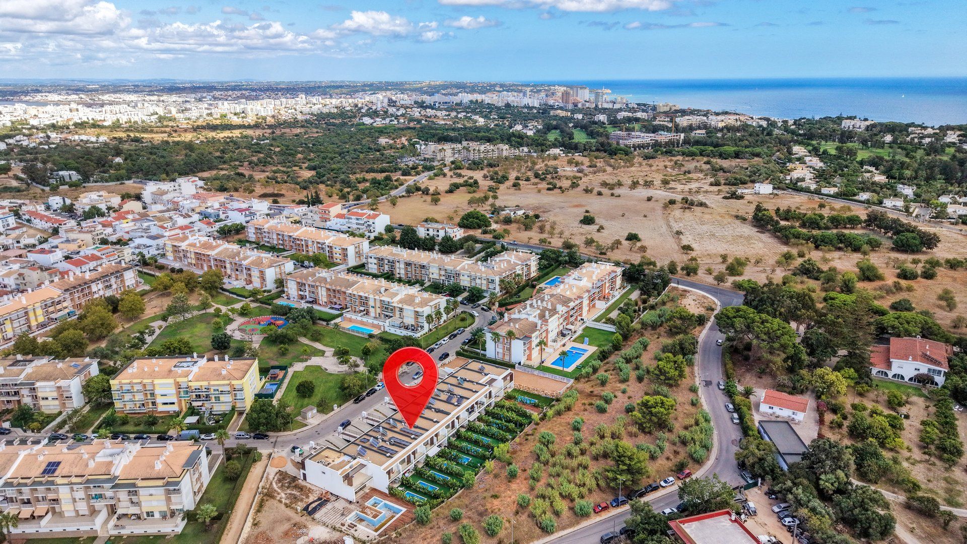 Vista aérea de una zona residencial con edificios de apartamentos, una carretera y un gran campo abierto.