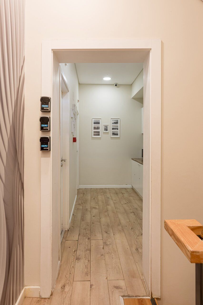 A hallway with wooden flooring, a white door, and a small table with a wooden top.