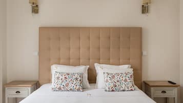 Una camera da letto con una testiera capitonné, due comodini con lampade e cuscini a motivi floreali.