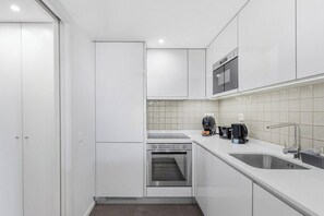 Eine moderne Küche mit weißen Schränken, einem Backofen, einer Spüle und einer Kaffeemaschine.