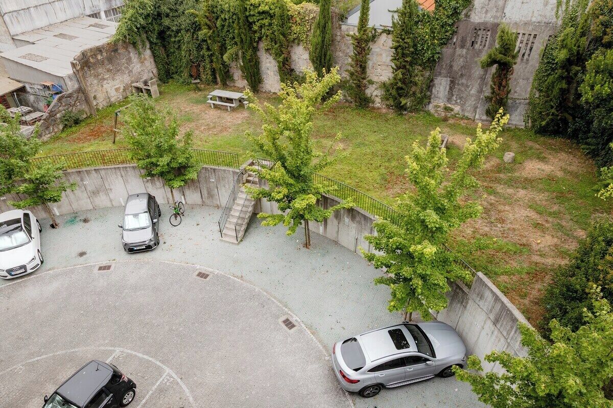 A parking area with cars, a bicycle, and a small bench.