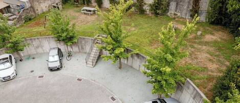 A parking area with cars, a bicycle, and a small bench.
