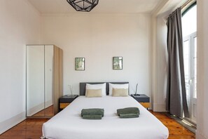 A bedroom with a large bed, two bedside tables, a wardrobe, and a window with curtains. - Bridge View Balcony, near LX Factory (Lisbon)