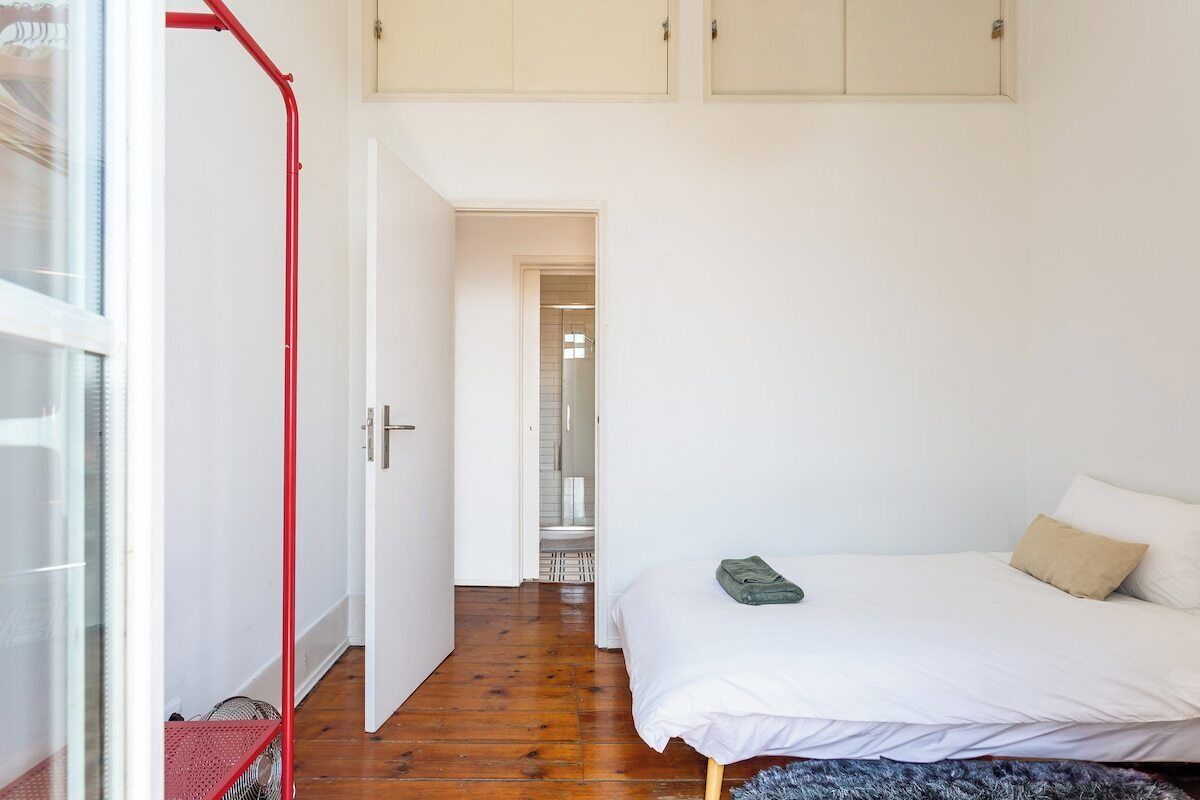 A bedroom with a bed, a red metal structure, and a white door leading to a bathroom.