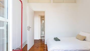 A bedroom with a bed, a red metal structure, and a white door leading to a bathroom.